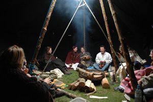 Schamanische Trommelgruppen - Menschen sitzen um ein Feuer im Zelt